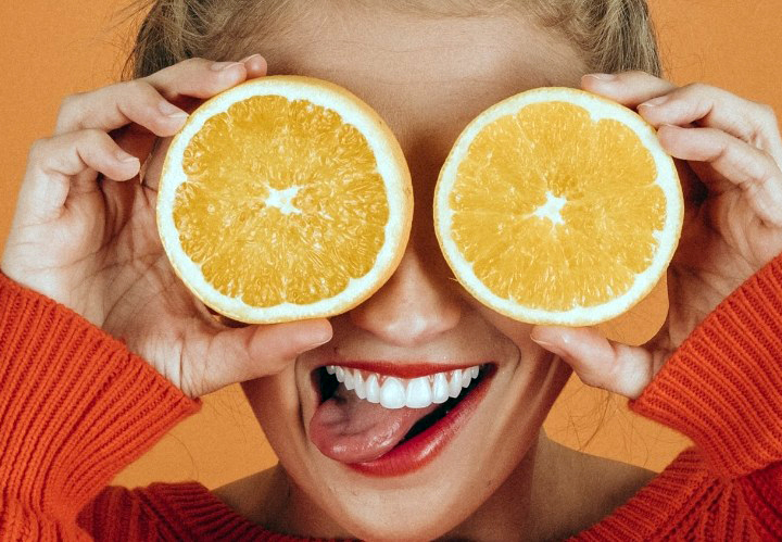woman covering her eyes with oranges